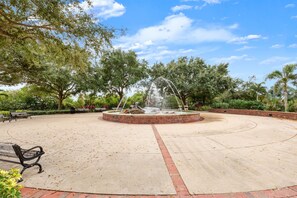 Un parque con una fuente circular, bancos y árboles.
