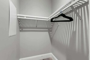 Una esquina de una habitación con un armario blanco y una percha para ropa.