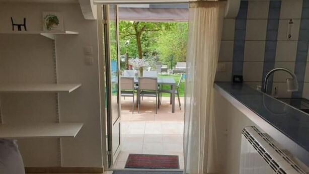 A kitchen with a view of an outdoor patio. - Studio Avec Jardin au Bord de la Rivière Avec Jacuzzi (Annot)