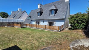 A modern house with a sloped roof, a fenced backyard, and a clear blue sky.