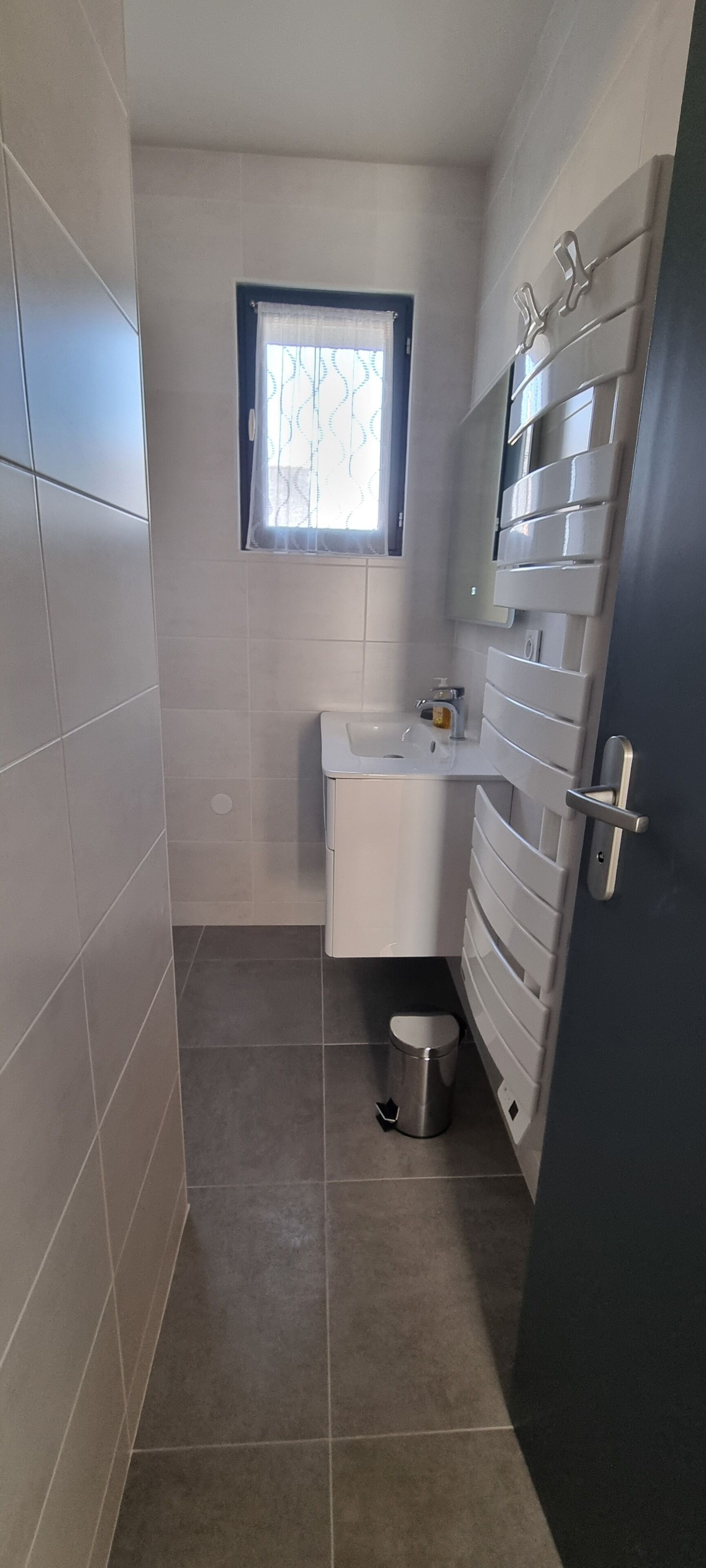 A small, modern bathroom with a toilet, sink, and a window.