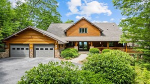 A log cabin with a garage, a covered porch, and a stone foundation. - Outstanding Views! 5BR/4.5 BA/ Sleeps 14, Hot-Tub, Pool Table! (Maggie Valley)