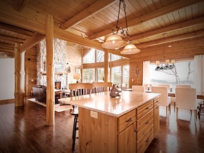 Un interior de madera con una isla central, pared de piedra y ventanas amplias.