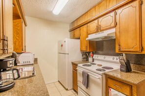 A kitchen with wooden cabinets, a white refrigerator, a stove, and a microwave. - A bedroom in close proximity to Fort Sill! (Lawton)