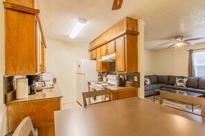 A compact kitchen with wooden cabinets, a refrigerator, a stove, and a dining table with chairs. - A bedroom in close proximity to Fort Sill! (Lawton)