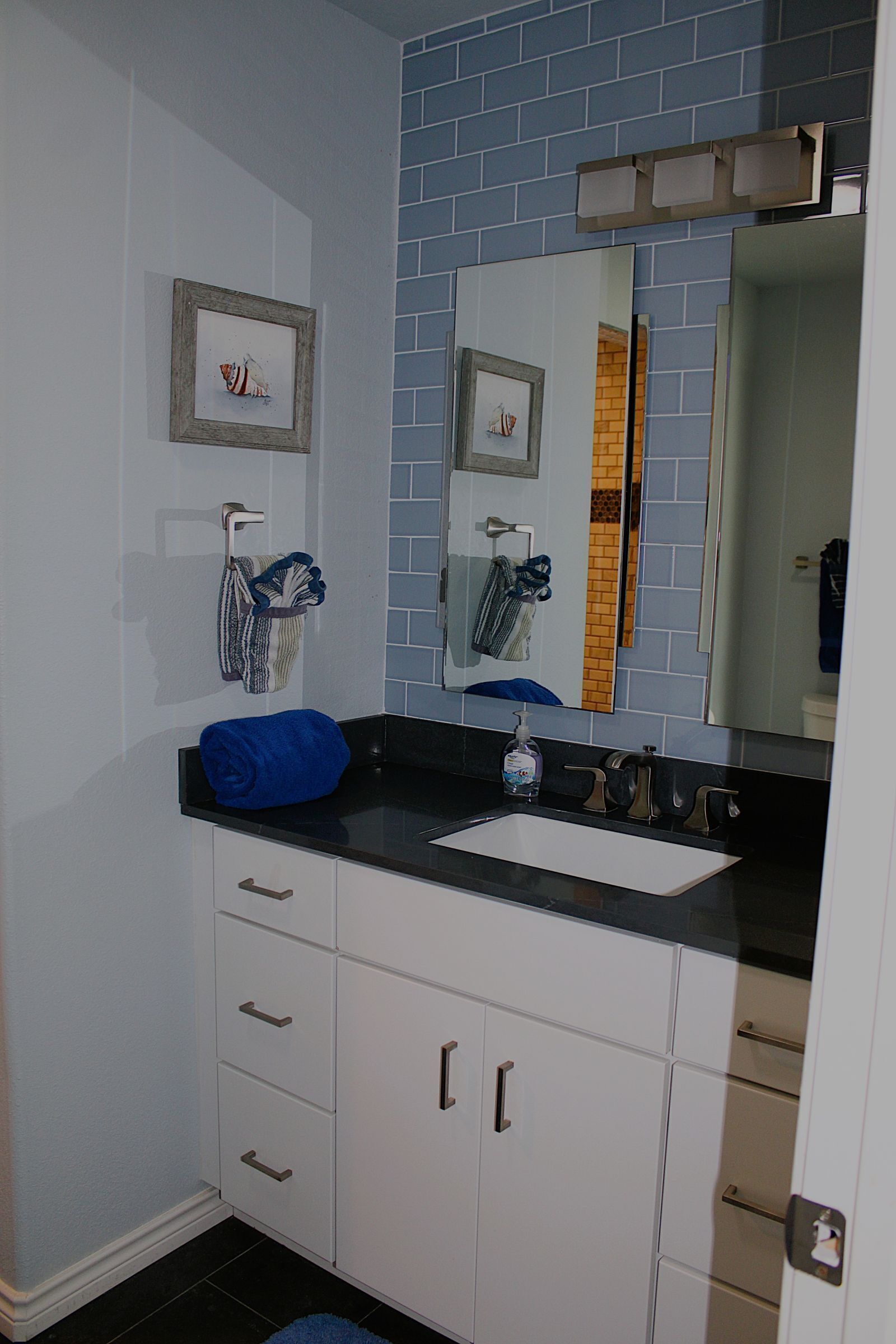 Ein Badezimmer mit einem weißen Waschbecken, einem Spiegel und einem blauen Handtuch auf der Ablagefläche.