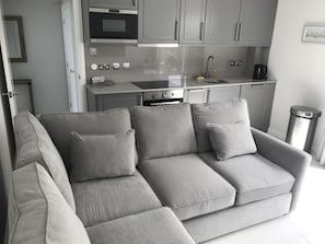 Een moderne keuken met grijze kastjes, een inbouwoven en een spoelbak.