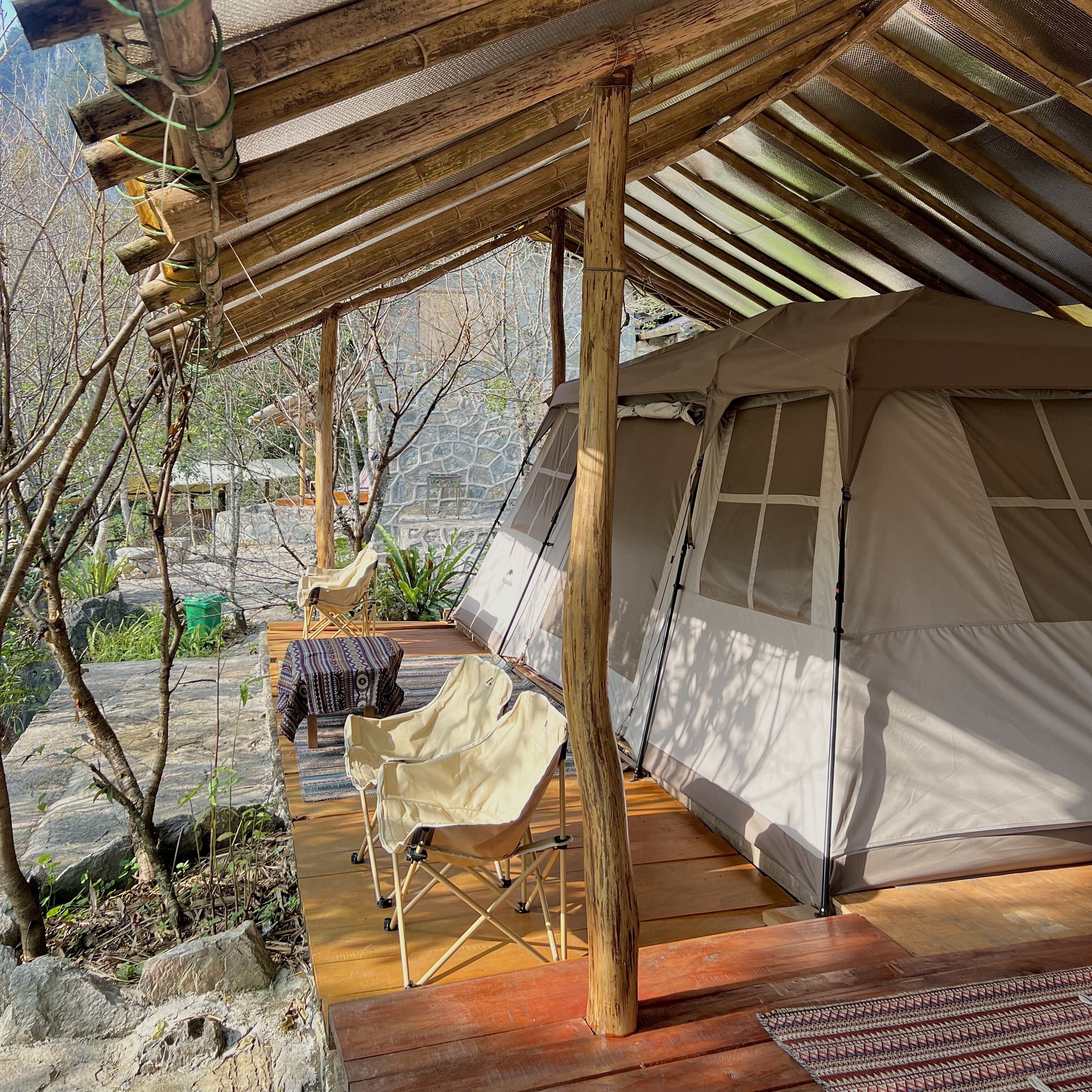 Un alojamiento en tienda de campaña con terraza de madera, una silla plegable y una mesa.
