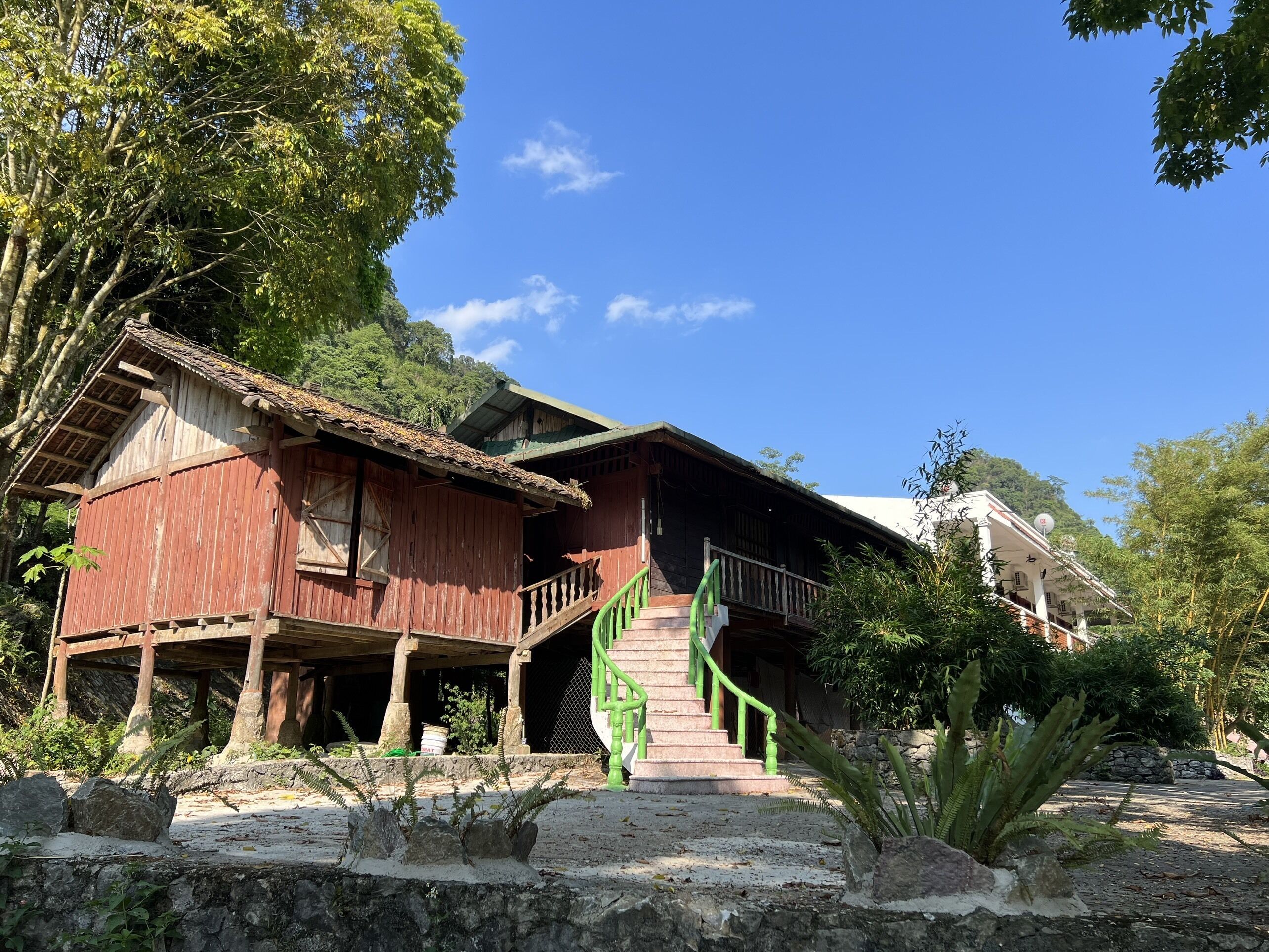 A rustic wooden house with a balcony and a staircase leading to the entrance.