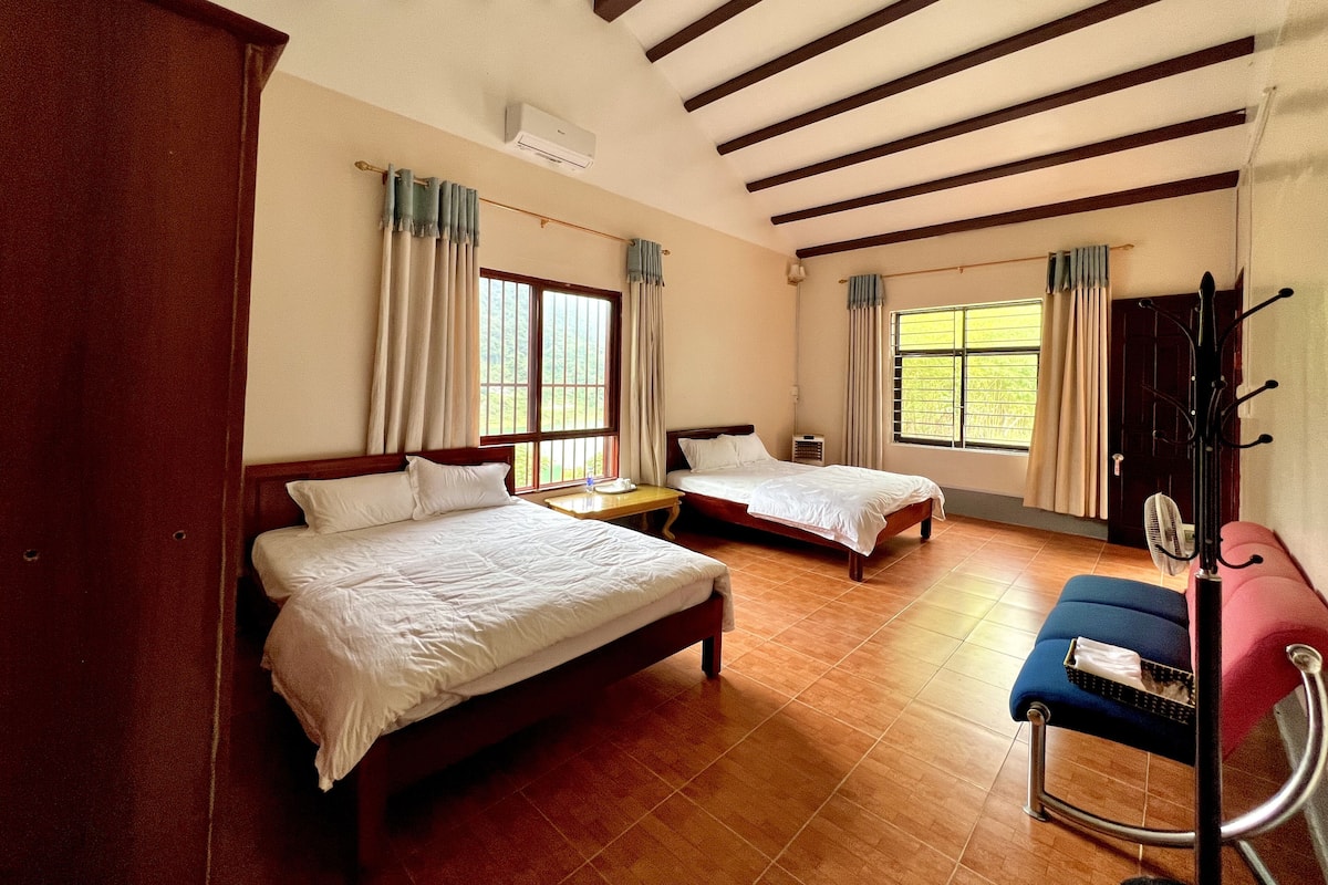 Une chambre d’hôtel avec deux lits, un plancher en bois, un bureau, une chaise et un porte-manteau.