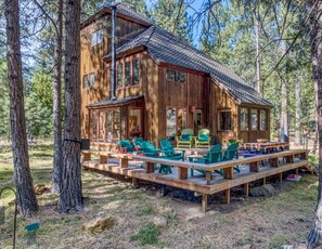 Une cabane en bois dotée d’une terrasse, de nombreuses fenêtres et d’un espace salon extérieur.