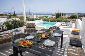 Ein Restaurant mit Pool, Sitzgelegenheiten im Freien und einem schönen Ausblick vom Dach.
