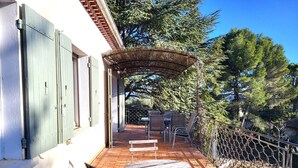 An outdoor patio with a table and chairs, a pergola, and a view of trees. - Au Centre du Village, Maison Avec Beau Jardin Arboré , Piscine Chauffée (Saint-Saturnin-lès-Apt)