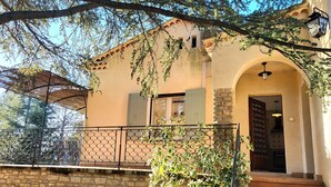 A building with a stone wall, a metal railing, and a staircase leading to an entrance. - Au Centre du Village, Maison Avec Beau Jardin Arboré , Piscine Chauffée (Saint-Saturnin-lès-Apt)
