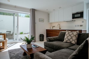 Een moderne woonkamer met een bank, een salontafel en een plant. Er is een schuifdeur naar een balkon.