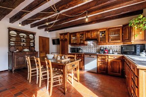 Uma cozinha com armários de madeira, uma mesa de jantar com cadeiras, um revestimento de azulejos e uma luminária pendente.