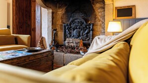 A cozy room with a stone fireplace, a wooden chest, and a comfortable sofa. - La Maison de Barbara (La Guiche)