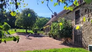A courtyard with a stone building, a paved path, and greenery. - La Maison de Barbara (La Guiche)
