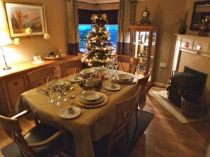 Een eetkamer met een kerstboom, een open haard en een televisie.