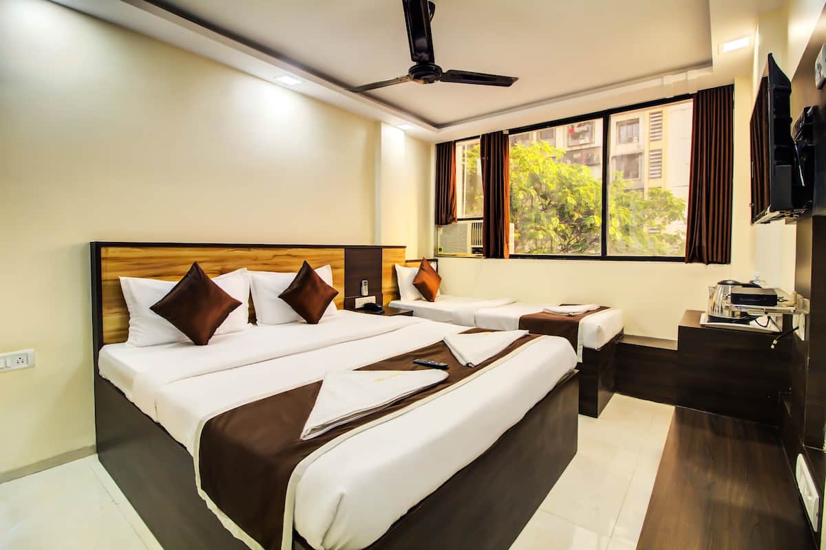 Quarto de hotel com uma cama grande, uma cama menor, uma escrivaninha e uma televisão.