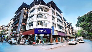 A multi-story hotel with a prominent 'PAL' sign, featuring a corner entrance and a visible outdoor seating area. - OPAL COMFORTS- A BUSINESS HOTEL (Navi Mumbai)
