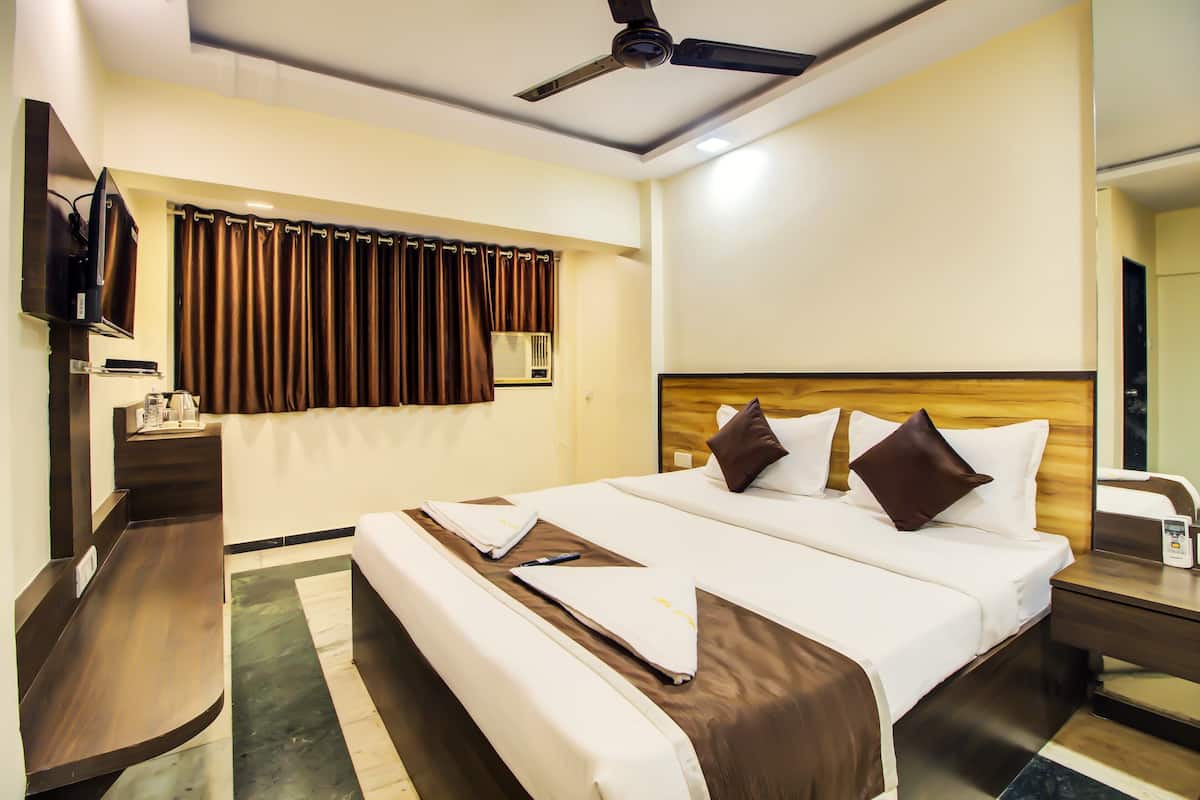Quarto de hotel com cama grande, escrivaninha, televisão e ventoinha no teto.