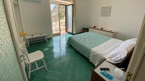 Une chambre à coucher avec un lit, une chaise, une table de chevet et une fenêtre.
