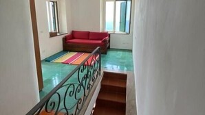 Un escalier avec une rampe en métal menant à un palier où se trouvent un canapé rouge et un tapis coloré.