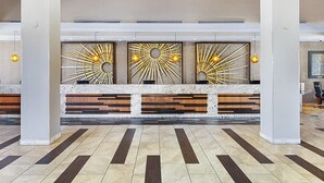 A reception area with a marble counter, wooden benches, and a sunburst wall decoration.