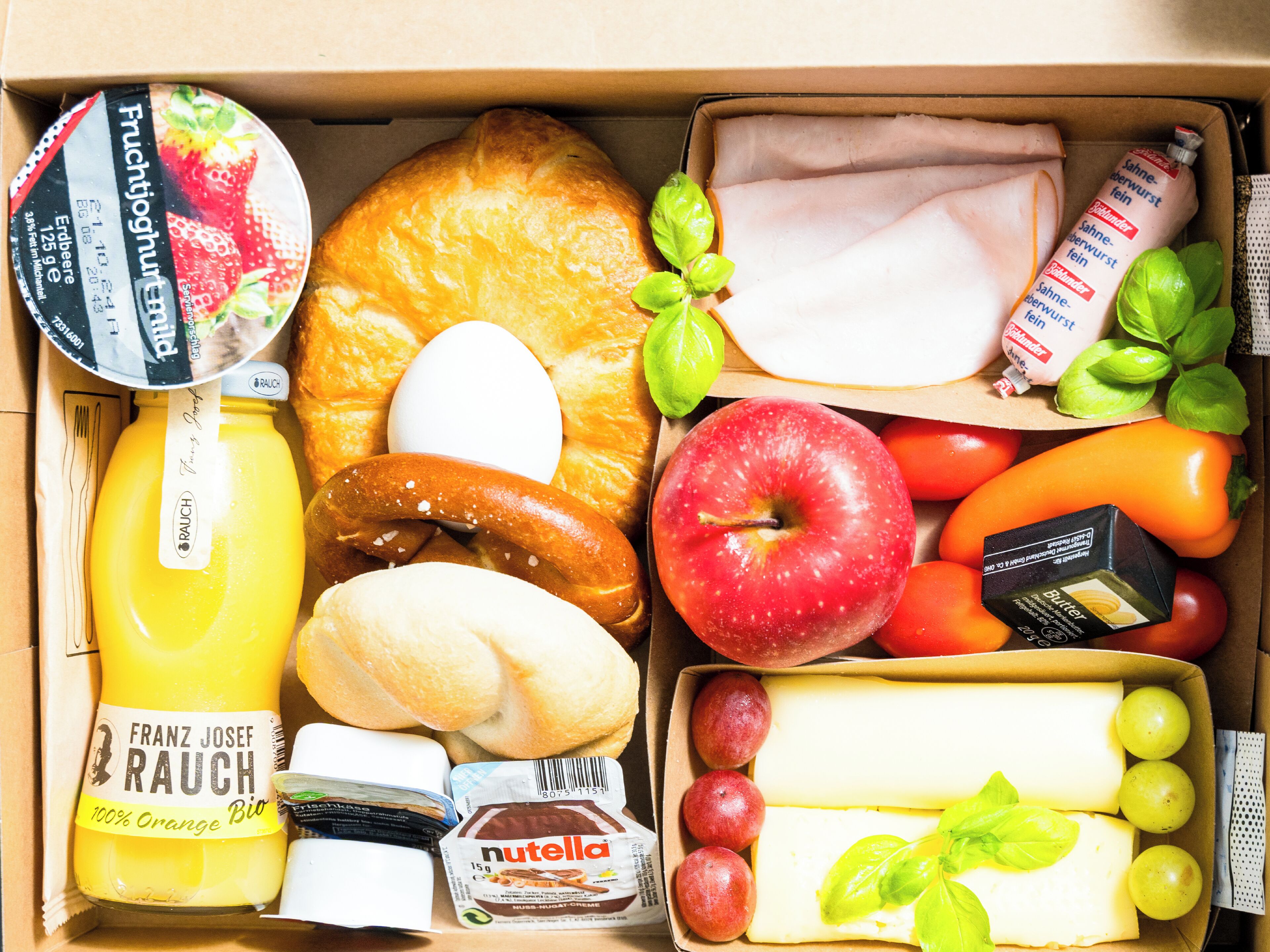 A variety of food items including bread, cheese, apples, tomatoes, and a bottle of orange juice.