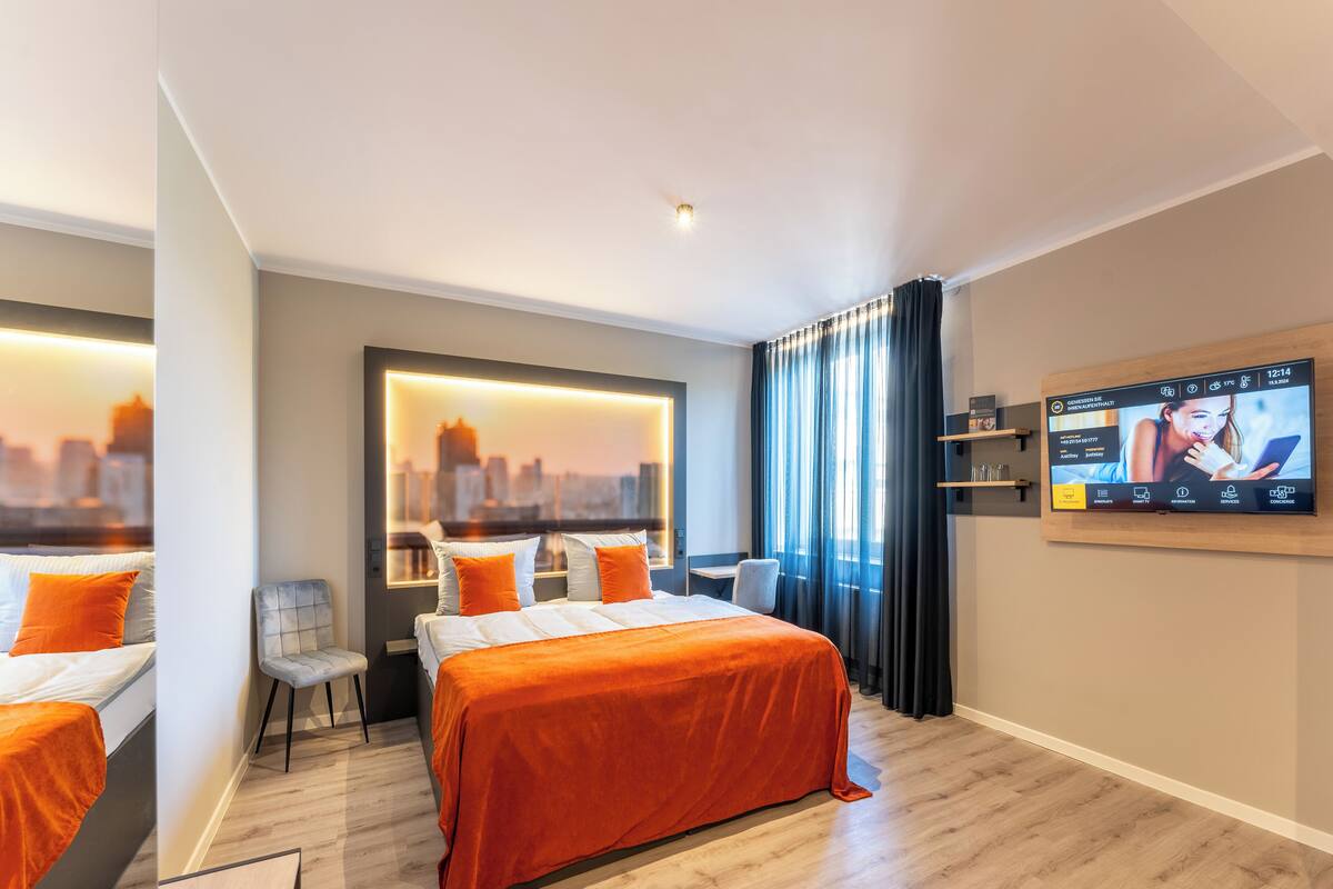 A modern hotel room with a large bed, a desk, and a city view.
