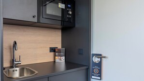 Uma cozinha moderna com uma pia de aço inoxidável, um micro-ondas e um relógio digital.