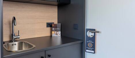 Una cocina moderna con un lavamanos de acero inoxidable, un microondas y un reloj digital.