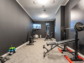 Un gimnasio en casa con equipo de ejercicio, un televisor y un espejo.
