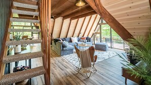 A cozy loft-style room with a wooden ceiling, a sofa, a coffee table, and a wicker chair. - Fox Hollow by Innsbrook Vacations! (Innsbrook)
