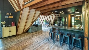A loft-style room with exposed wooden beams, a bar area with stools, and a kitchenette. - Fox Hollow by Innsbrook Vacations! (Innsbrook)