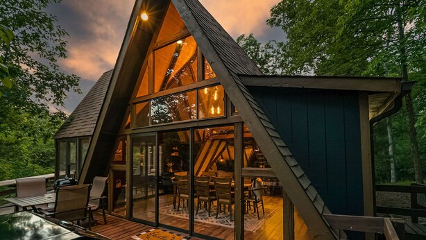 A modern, triangular wooden cabin with large windows and a deck area. - Fox Hollow by Innsbrook Vacations! (Innsbrook)