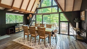 A dining area with a wooden table and chairs, large windows, and a view of the outdoors. - Fox Hollow by Innsbrook Vacations! (Innsbrook)