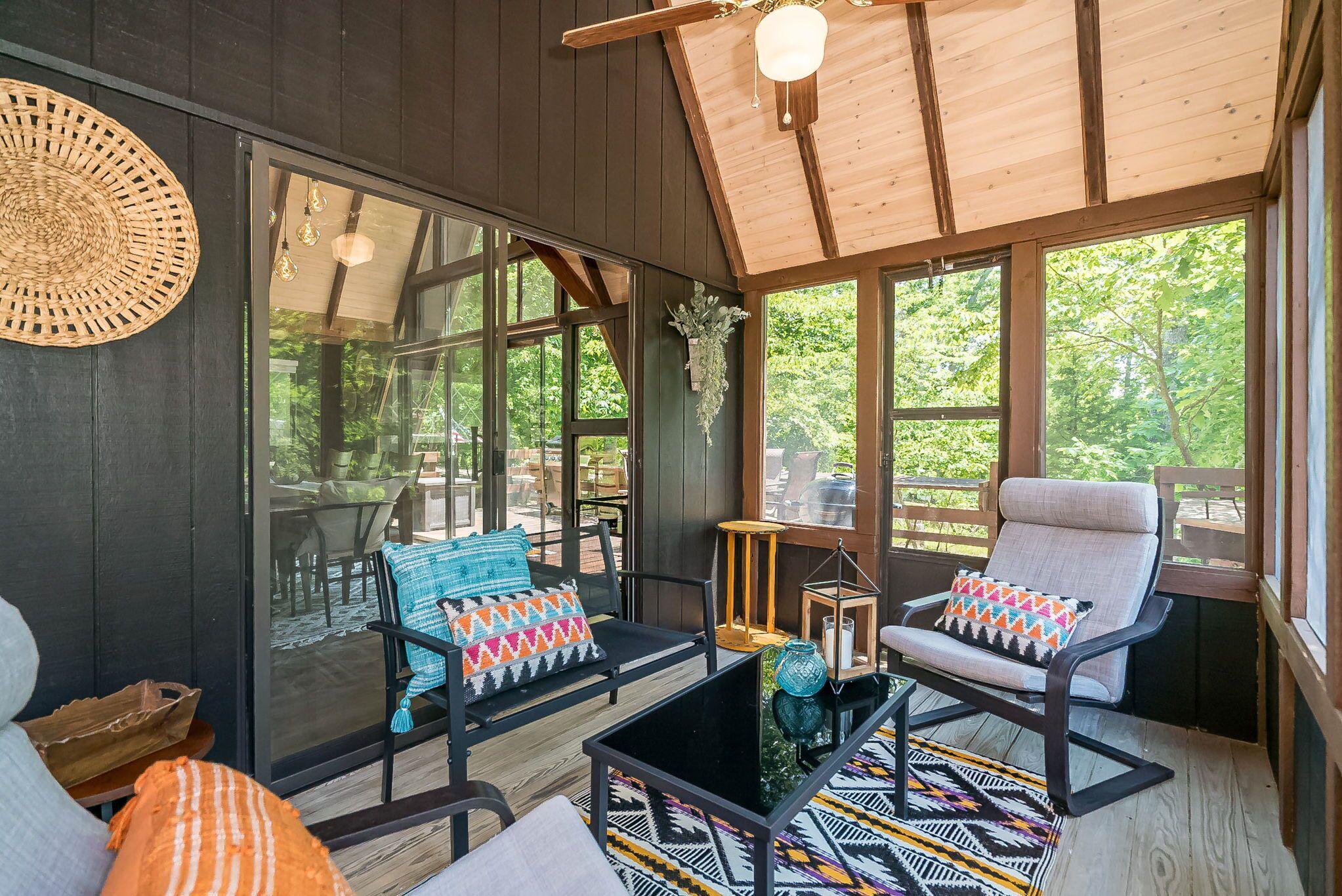A cozy room with a large window, a wooden ceiling, and a glass door leading outside.