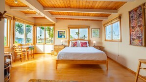 A bedroom with a wooden bed, large windows, and a view of palm trees.
