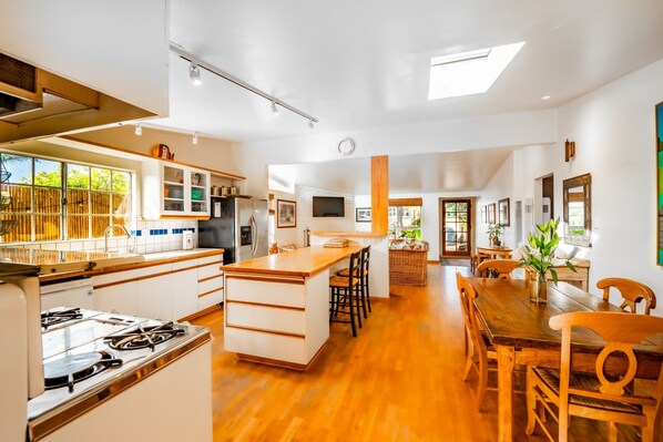 Una cocina amplia con una isla central, suelo de madera y un comedor con mesa y sillas de madera.