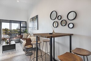 Um espaço de estar moderno com área de jantar, sofá e uma janela grande.
