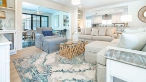 A spacious living room with a large sectional sofa, a coffee table, and a patterned rug. There is a dining area visible in the background. - Welcome to your personal slice of paradise (Placida)
