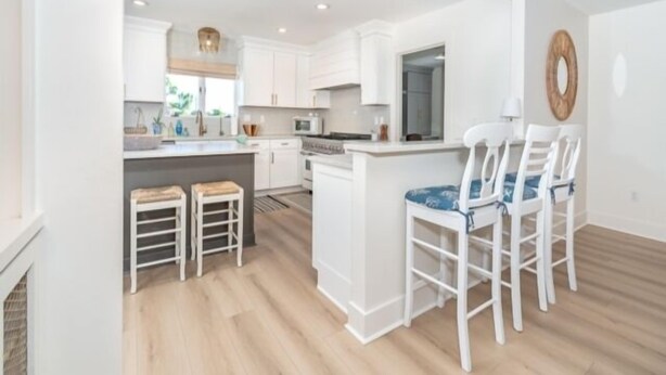 A modern kitchen with white cabinetry, a central island, and a dining area with white chairs. - Welcome to your personal slice of paradise (Placida)