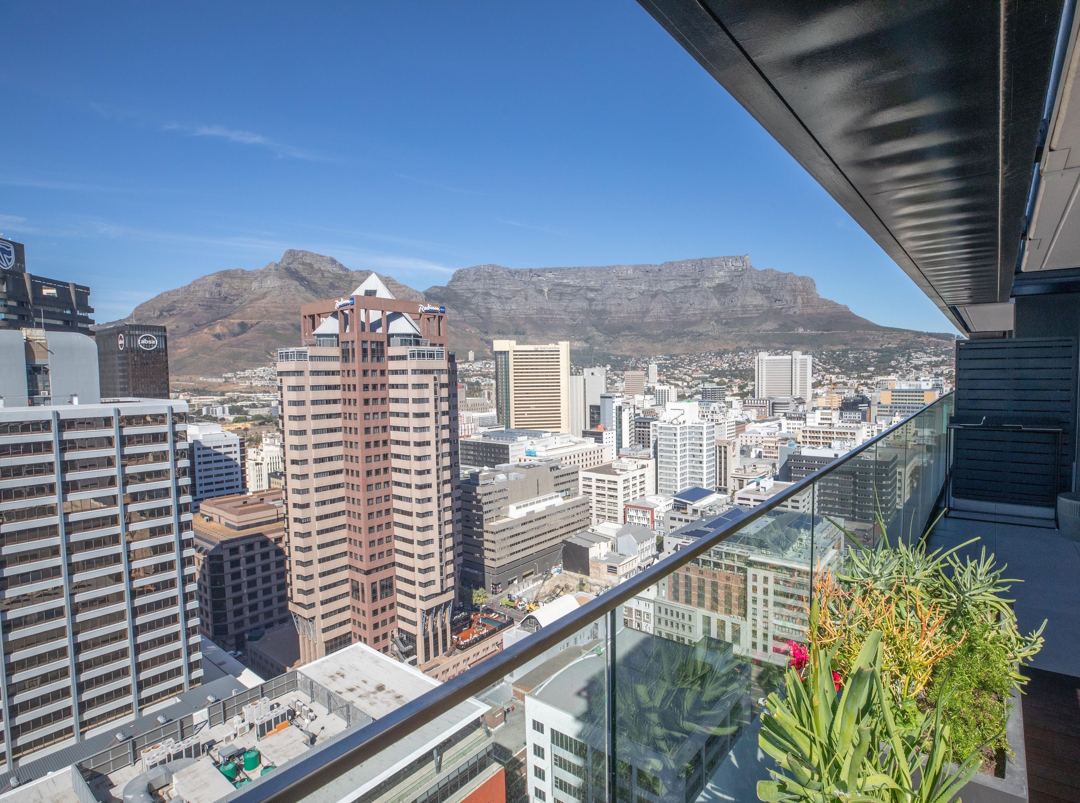 A high-rise building with a view of a cityscape and mountains in the background.