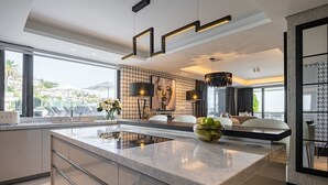 A modern kitchen with a large island, pendant lighting, and a view of the outdoors. - Aurum 101 - Two Bedroom Apartment, Sleeps 4 (Cape Town)