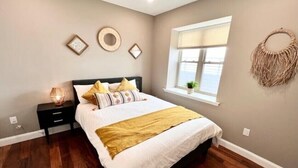 Ein Schlafzimmer mit Bett, Nachttischen, einem Fenster und Wanddekoration.