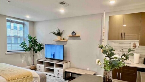 A modern bedroom with a bed, TV, bedside table, and a small kitchenette. - 308 Cozy and warm  King Bed APT in center city
 (Philadelphia)