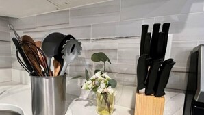 A kitchen counter with a stainless steel utensil holder, a small vase with flowers, and a knife block. - 304 Stunning and comfy  1BDR APT in Center city (Philadelphia)