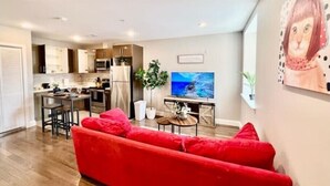 A modern living room with a red sofa, a TV, and a kitchen in the background. - 304 Stunning and comfy  1BDR APT in Center city (Philadelphia)